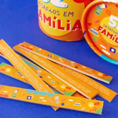 Jogo '52 Desafios em Família' com embalagem amarela e cartões coloridos sobre fundo azul