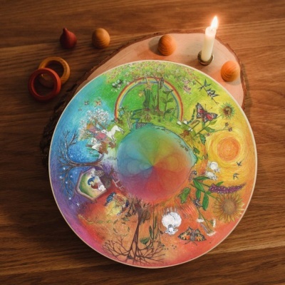 Placa circular ilustrada com estações do ano e natureza sobre base de madeira com vela acesa