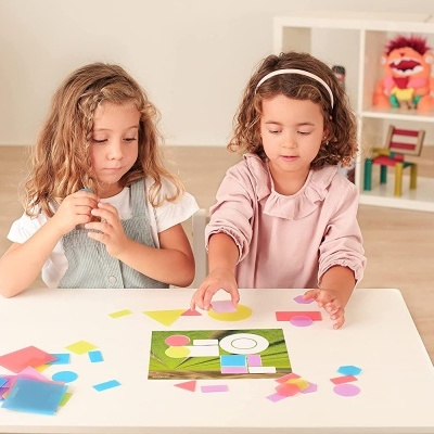 duas crianças a brincar com peças geométricas coloridas numa mesa branca