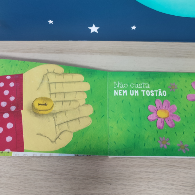 Página de livro infantil com mão amarelo segurando moeda e texto em português.