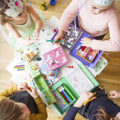 Crianças a pintar com lápis de cor em livros de colorir com temas de unicórnios e animais