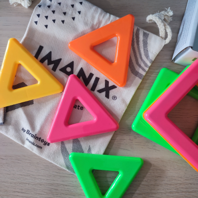 Peças triangulares coloridas em saco de tecido IMANIX sobre mesa de madeira