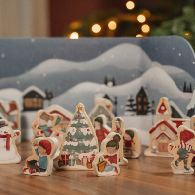 Figuras decorativas de Natal em madeira com crianças, árvores, boneco de neve e casas sobre superfície de madeira