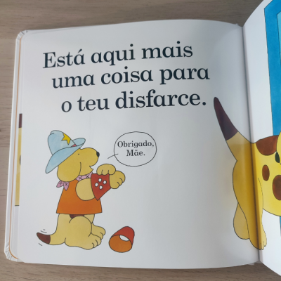 Página de livro infantil com cão amarelo vestido com chapéu azul estrela e colete, texto em português