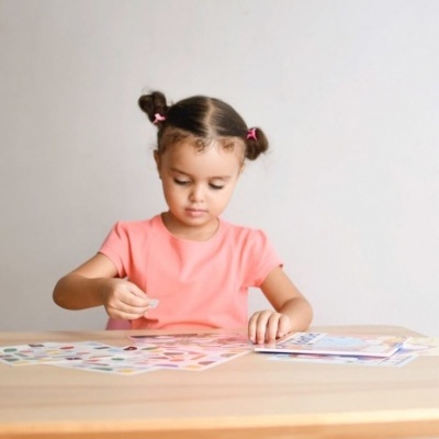 Criança a colar autocolantes numa mesa