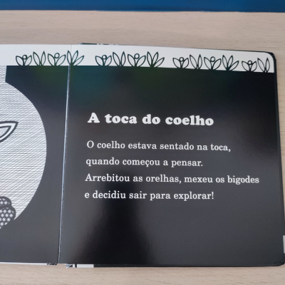 Página de livro infantil com texto sobre o coelho e decoração de folhas na borda superior