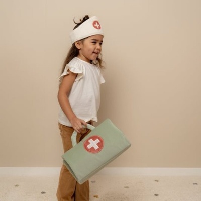 Criança com traje de médico segurando mala verde com cruz vermelha e branca