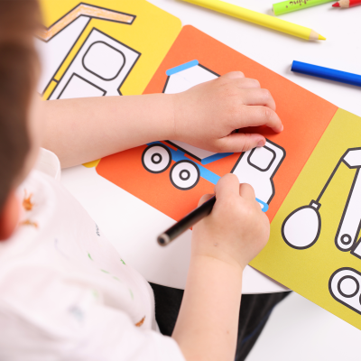 Criança a colorir livros de atividades sobre veículos de construção