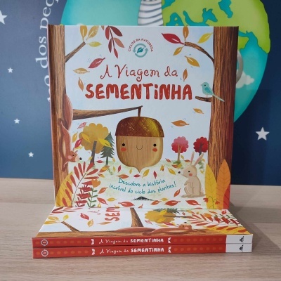 Capa do livro infantil A Viagem da Sementinha com ilustrações coloridas e três livros empilhados