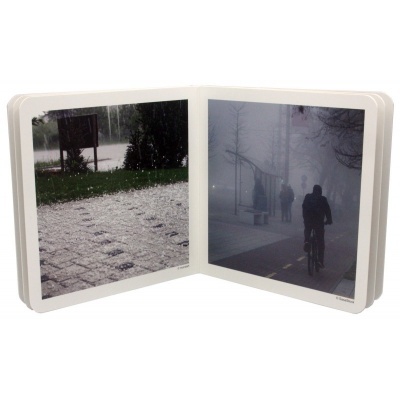 Livro aberto com duas fotografias, uma de caminho de pedra com vegetação e outra de pessoa de bicicleta em rua nevoenta