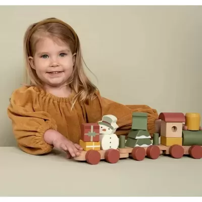 Criança a brincar com comboio de madeira colorido com boneco de neve e casa