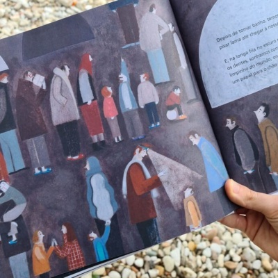 Livro ilustrado aberto com pessoas em roupas coloridas e texto