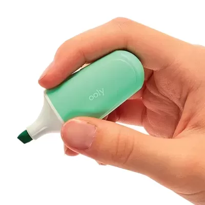 Marcador de texto verde da marca ooly segurado por uma mão