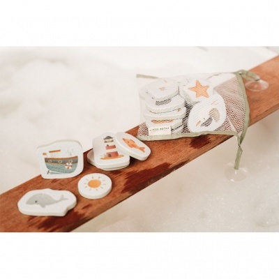 Peças de madeira com desenhos marinhos e saco de rede branco em tábua de madeira