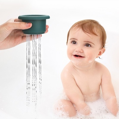 bebé sorridente na banheira com espuma e um doseador de água verde escuro