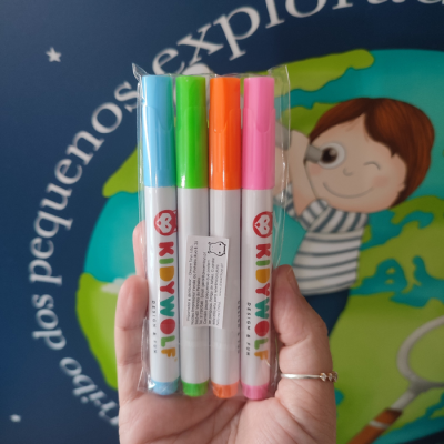 Quatro marcadores KIJIWOLF em diferentes cores embalados em plástico, segurados por uma mão.