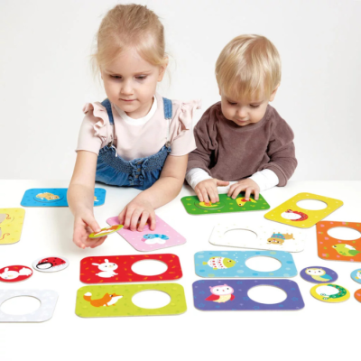 Duas crianças a jogar com cartas de animais coloridas num jogo educativo