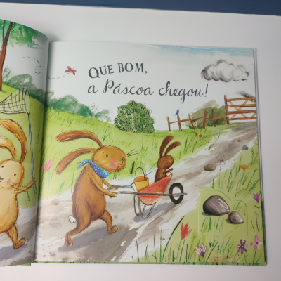Página de livro infantil com coelhos e texto 'QUE BOM, a Páscoa chegou!'