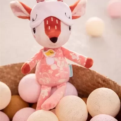 Boneco de pelúcia rosa com máscara de dormir sentado em cesta com bolas decorativas