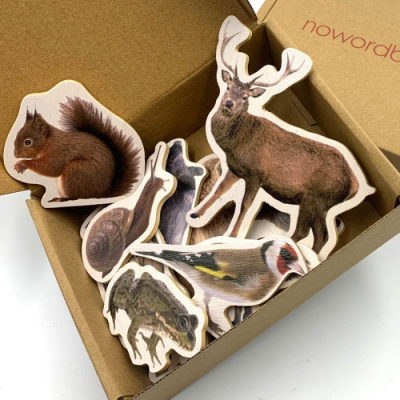 Placas de madeira em forma de animais da floresta dentro de uma caixa de cartão