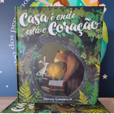 Capa de livro infantil com ilustração de raposa e urso numa árvore oca, título 'Casa é onde está o Coração'.