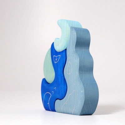 Peças de madeira azul e verde água com desenhos brancos, sobre fundo branco