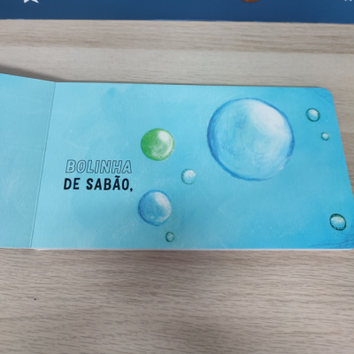Livro infantil aberto com ilustrações de bolhas de sabão e texto em português