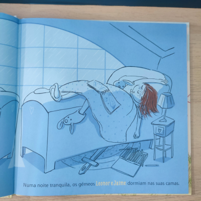 Ilustração de criança a dormir numa cama azul com candeeiro e mesa de cabeceira, texto em português