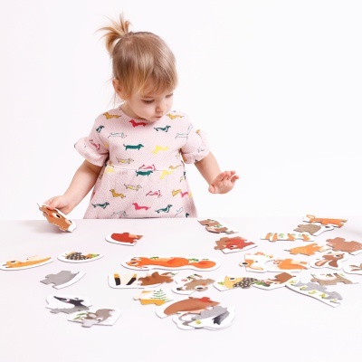 Criança a brincar com puzzle de madeira sobre mesa branca