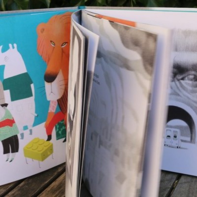 Livro infantil aberto com ilustrações coloridas e retrato em preto e branco