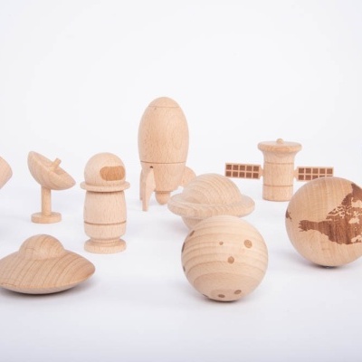 Figuras de madeira representando planetas e astronauta em fundo branco.