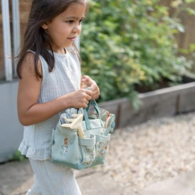 Criança a segurar bolsa de tecido azul claro com padrão floral em jardim