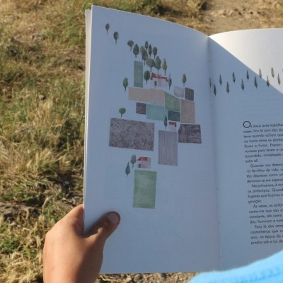 Pessoa a ler livro aberto ao ar livre com texto e imagens na página