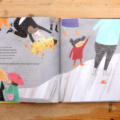 Livro infantil aberto com ilustrações coloridas, texto em português, sobre mesa de madeira