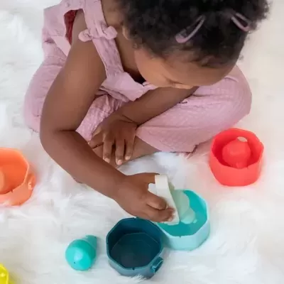 Criança a brincar com blocos de construção coloridos sobre tapete branco felpudo