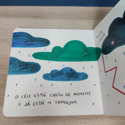 Página de livro infantil com ilustração colorida de nuvens e texto em português