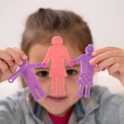 Criança segura figuras humanas de plástico rosa e roxo