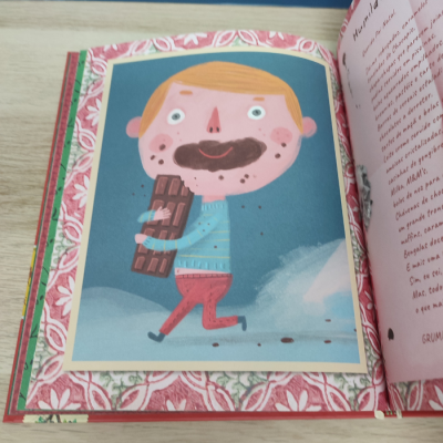 Ilustração de menino com barra de chocolate num livro aberto
