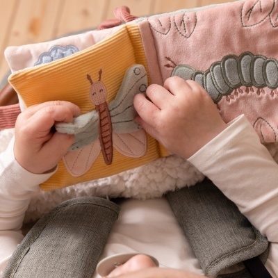 Bebé a segurar livro de tecido com borboleta bordada e almofada decorada com lagarta