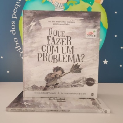 Capa do livro 'O QUE FAZER COM UM PROBLEMA?' com ilustração de criança e guarda-chuva cinzento