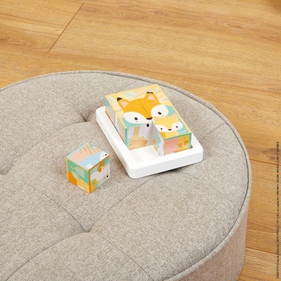 Blocos de madeira com raposas em almofada cinza sobre chão de madeira