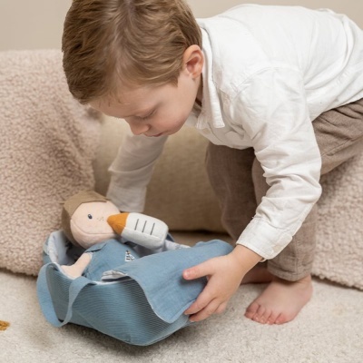 Criança a cobrir boneco de pano com cobertor azul em sala interior