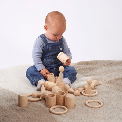 Criança a brincar com blocos de madeira natural sobre uma manta bege clara