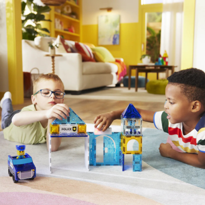 Crianças brincando com blocos de construção magnéticos formando uma estação de polícia e viatura