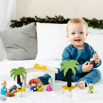 Criança em pijama azul brinca com brinquedos de madeira coloridos numa cama branca