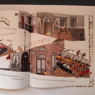 Página aberta de livro infantil com ilustrações de rua e texto em português