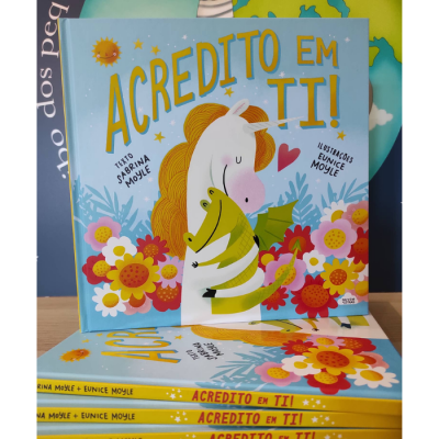 Capa de livro infantil azul claro com unicórnio e dragão, título ACREDITO EM TI!