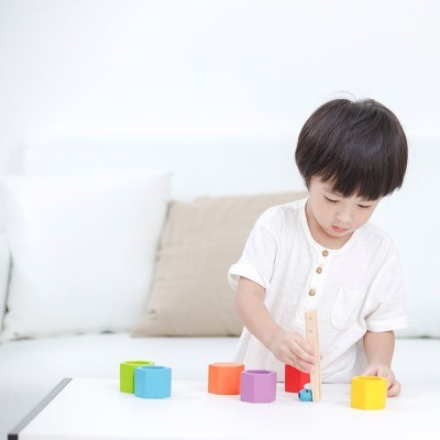 Menino a brincar com blocos de madeira coloridos numa mesa branca