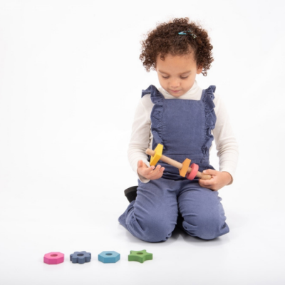 Criança com macacão azul a brincar com brinquedo de madeira colorido