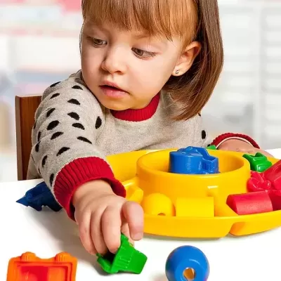 Criança pequena a brincar com brinquedo de encaixe colorido